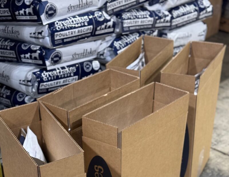 Pick and Pack example Pick and pack station with open cardboard boxes in front of stacked pet food bags, prepared for order fulfillment.